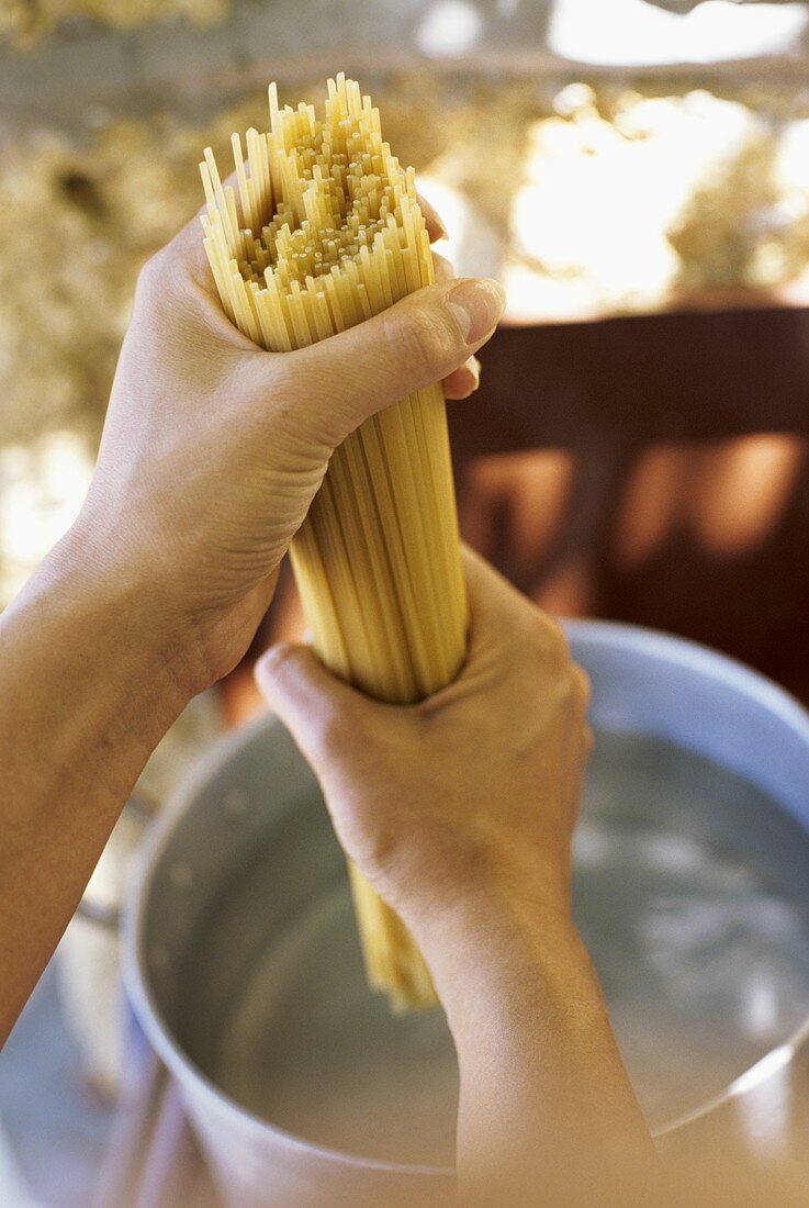 Spaghetti werden in einen Topf kochendes Wasser gegeben