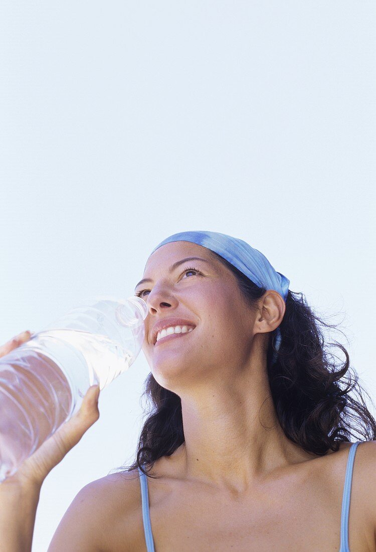 Young woman drinking mineral water in the open air