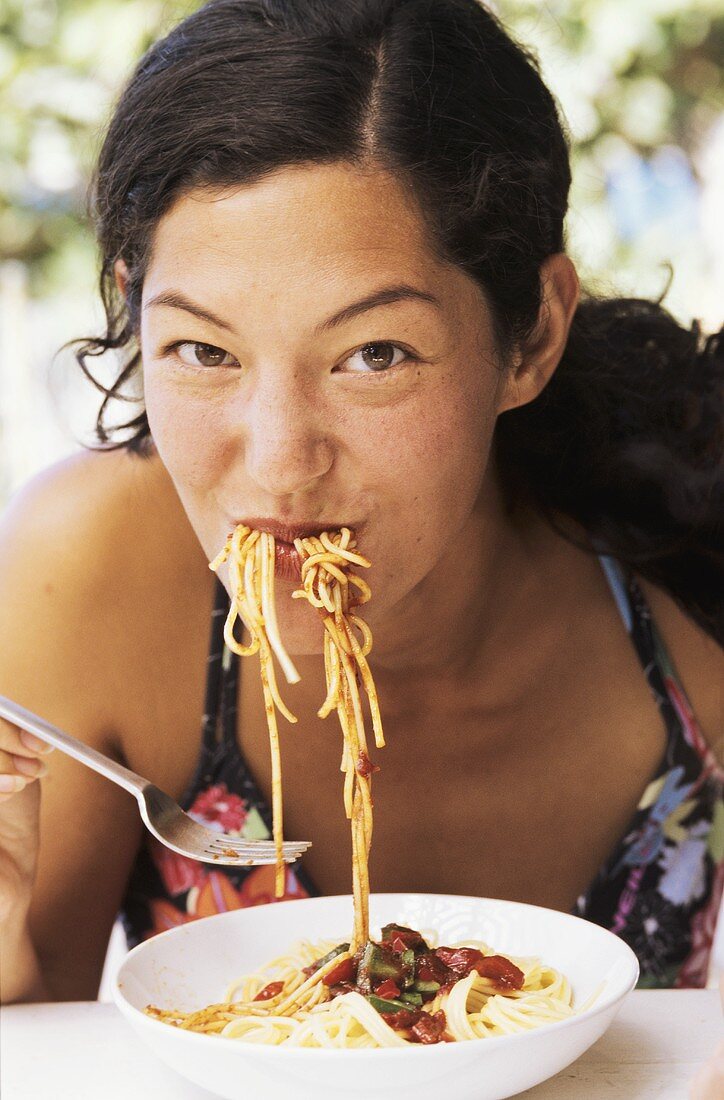 Young woman devouring spaghetti with tomato sauce