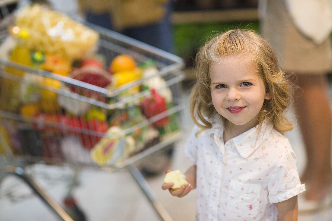 Kleines Mädchen mit Apfel im Supermarkt