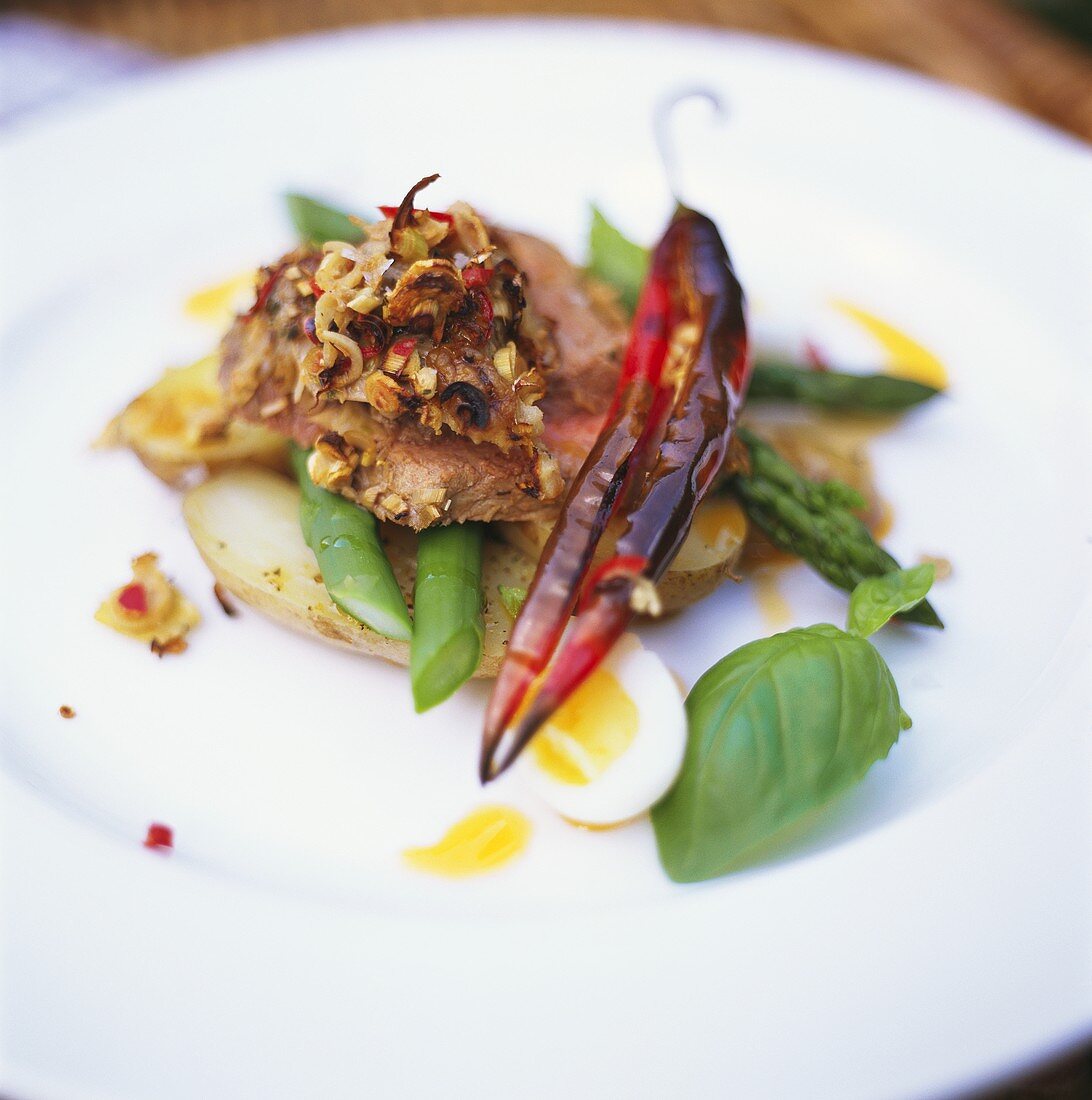 Roast beef with chili on green asparagus and potatoes