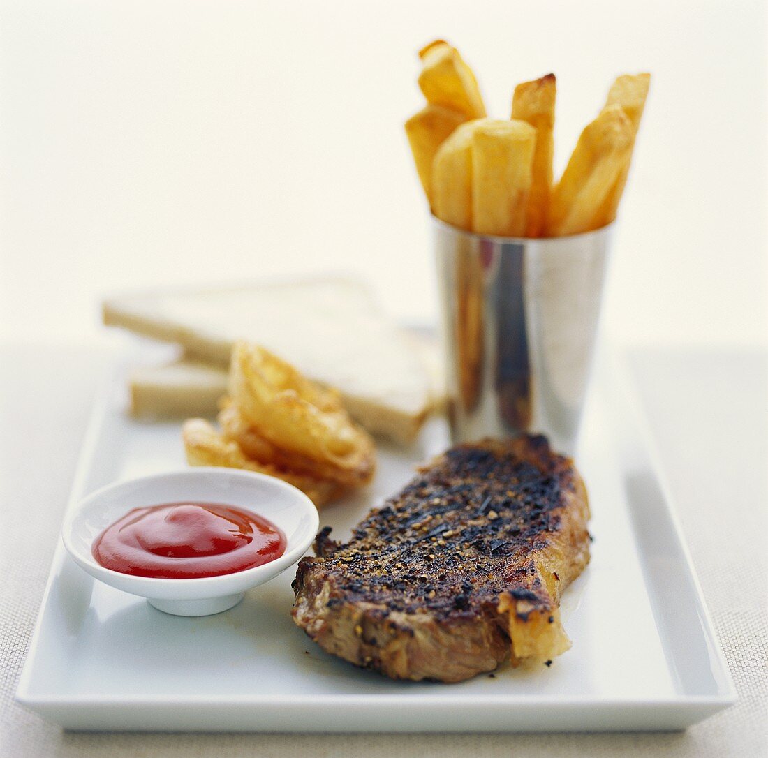 Peppered steak with chips, ketchup and sliced bread