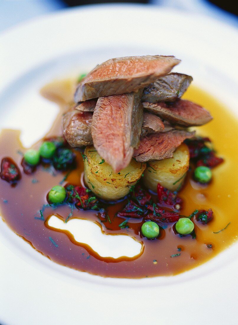 Lamb fillets on potatoes in beetroot sauce with peas