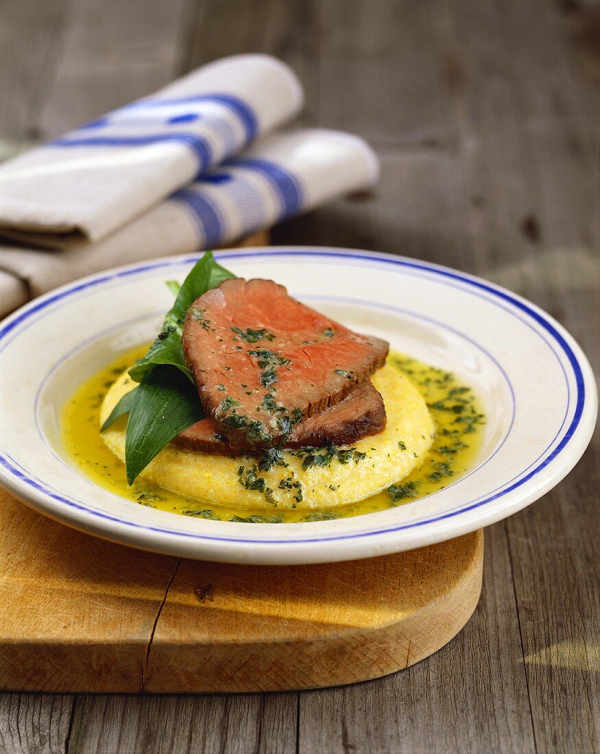 Roast beef with herb butter on polenta