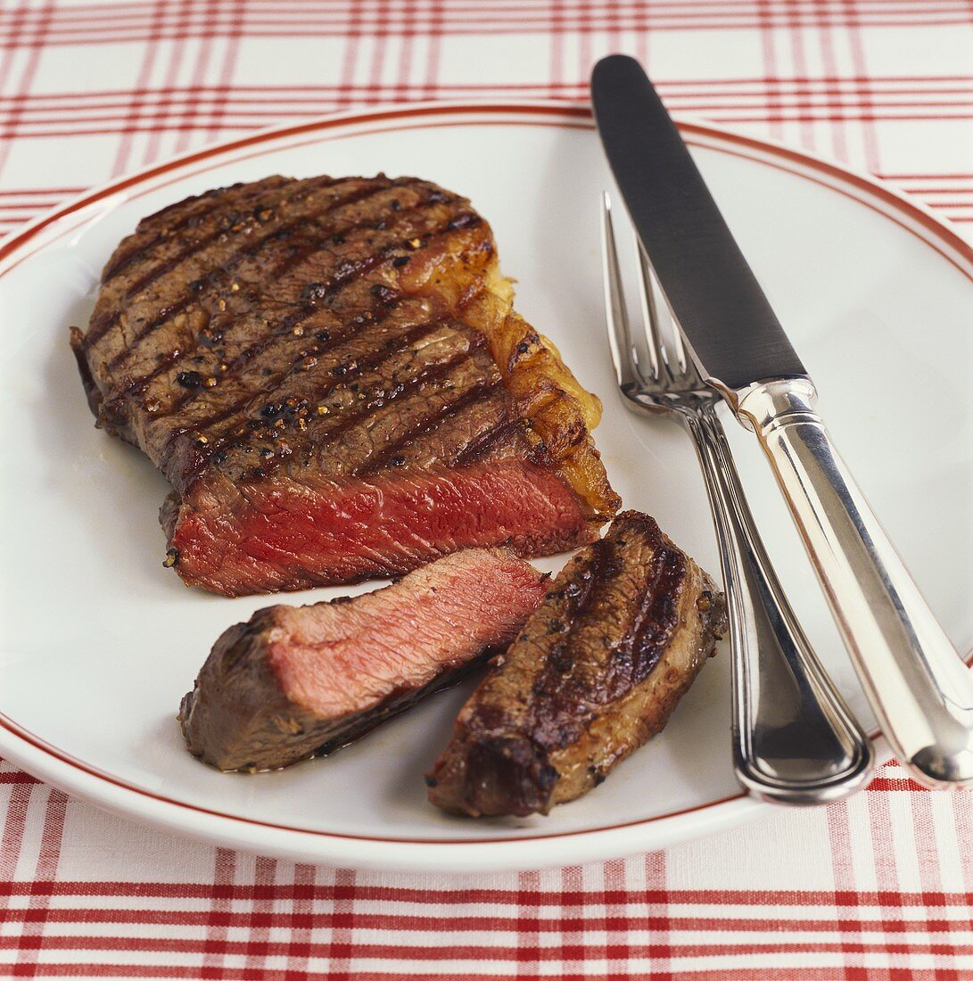 barbecued beef steak, a piece cut off, on plate