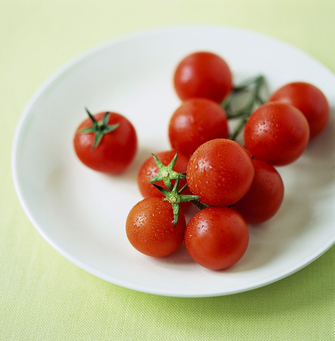 Cherry tomatoes with drops of water on white plate