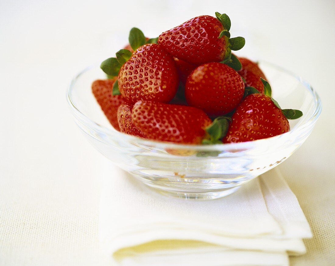 Strawberries with leaves in glass bowl