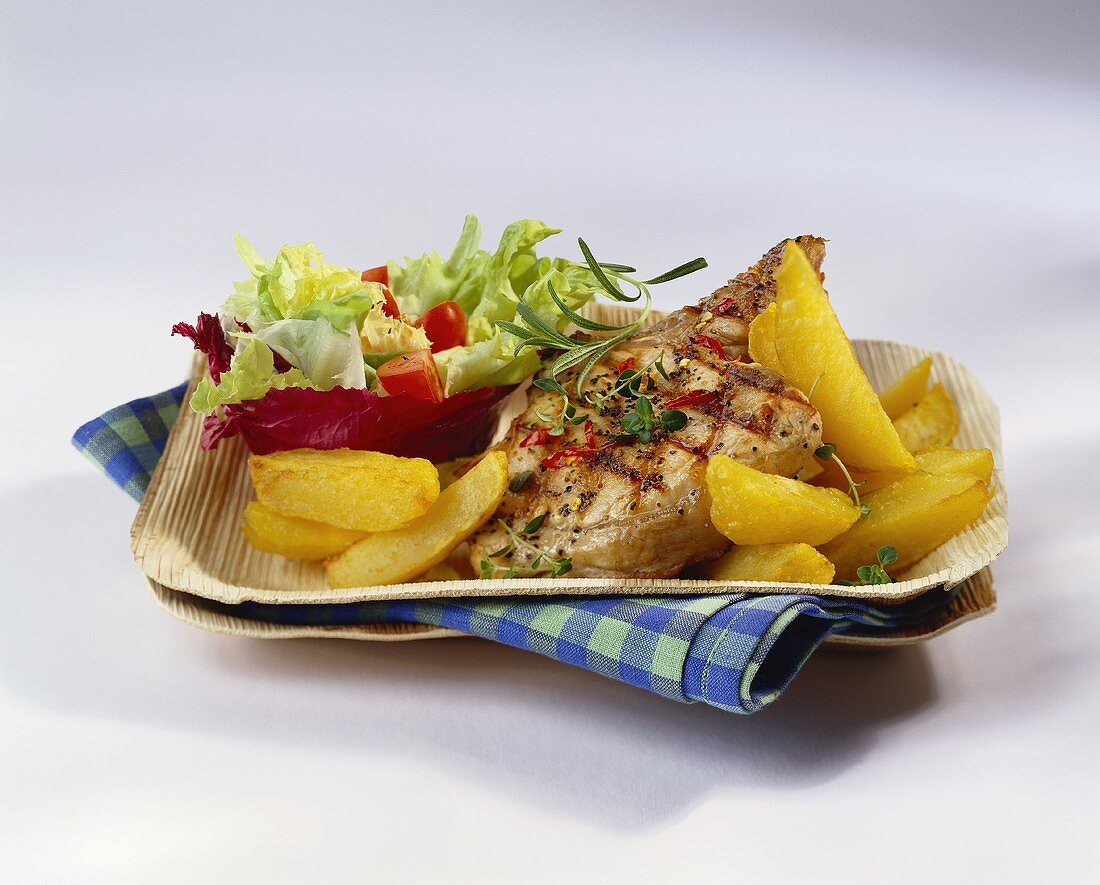 Barbecued pork chop with potato wedges and salad