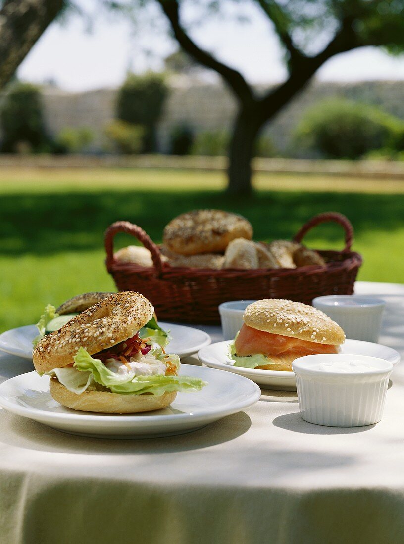 Bagels mit Lachs und Frischkäse auf Tisch im Garten