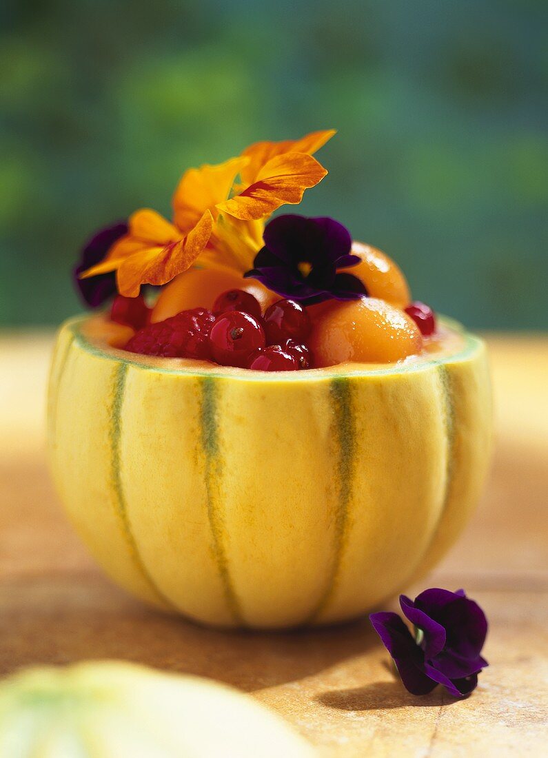Melon filled with summer fruit and flowers