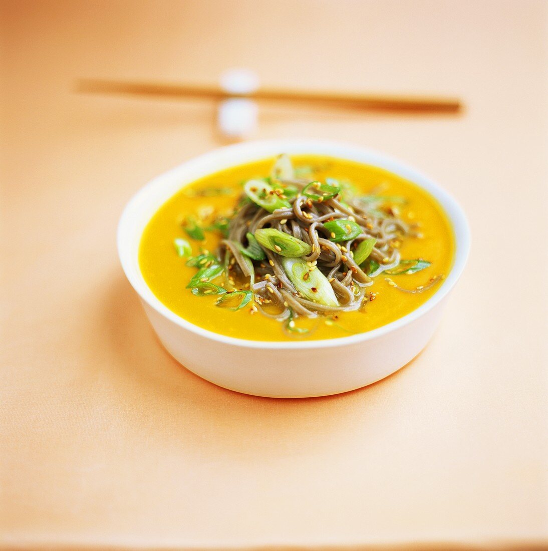 Carrot soup with soba noodles, sesame and spring onions
