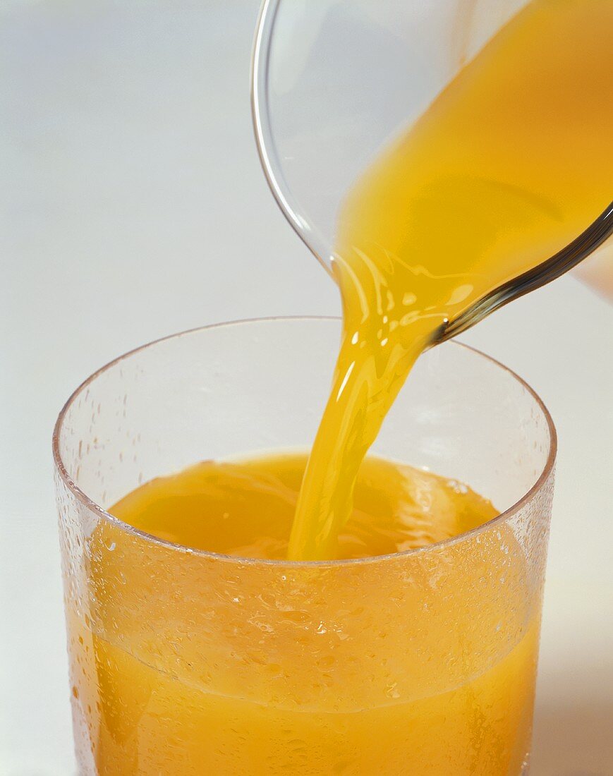 Orangensaft in Glas gießen