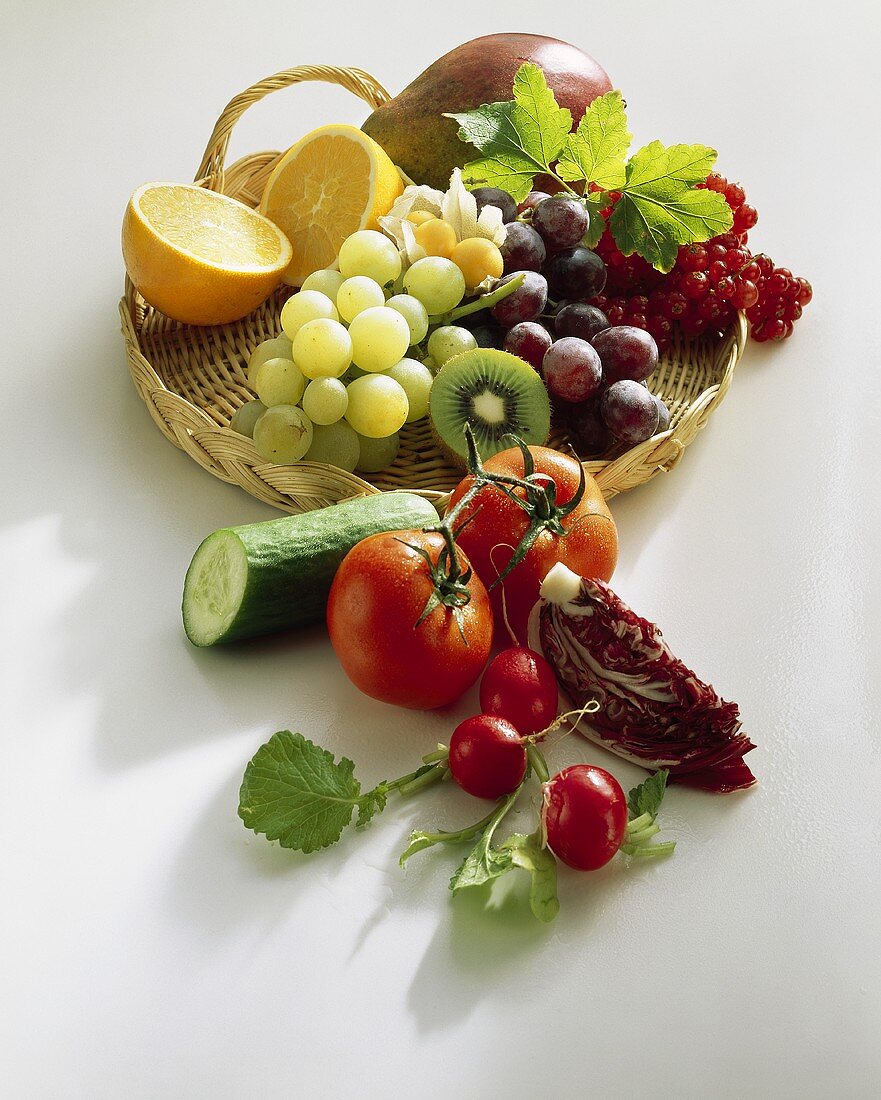 Fresh fruit on wicker tray, vegetables in front