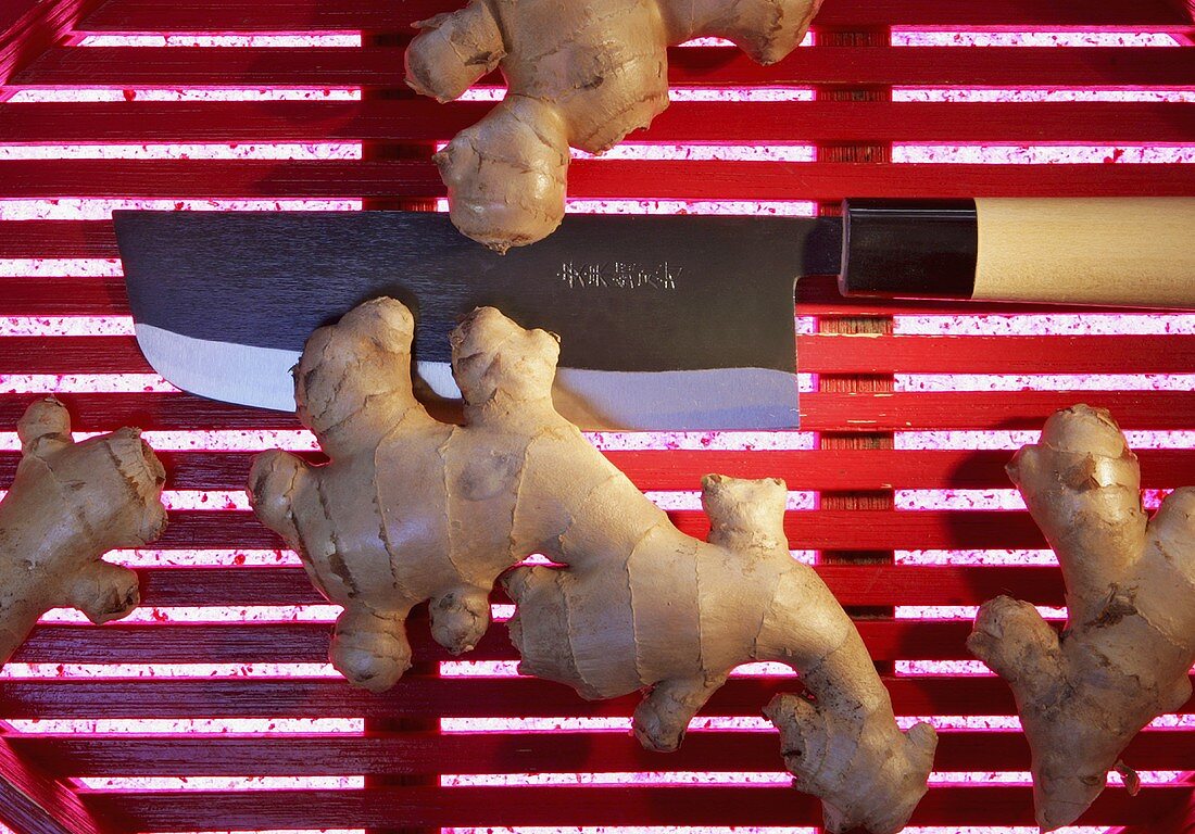 Ingwerwurzel mit asiatischem Messer auf rotem Tablett