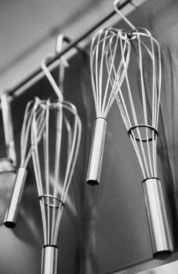 Several whisks hanging in a kitchen
