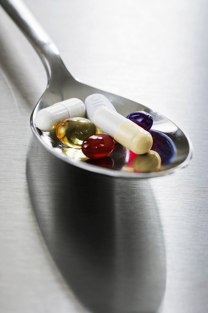 An assortment of capsules and tablets on spoon