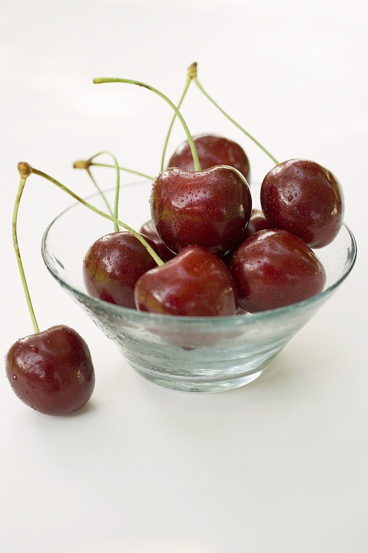 Cherries with drops of water in glass bowl