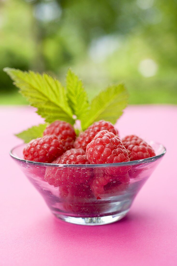Raspberries with leaf in glass bowl