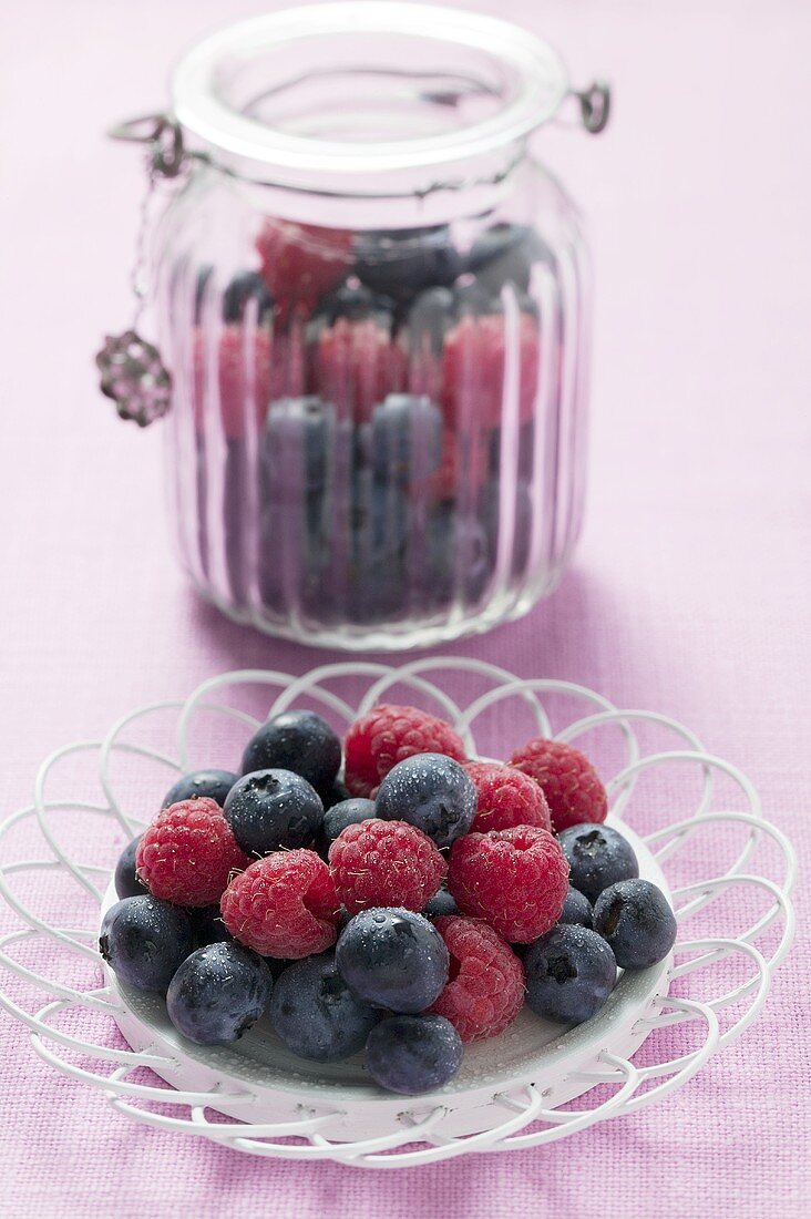 Blueberries and raspberries on plate and in storage jar