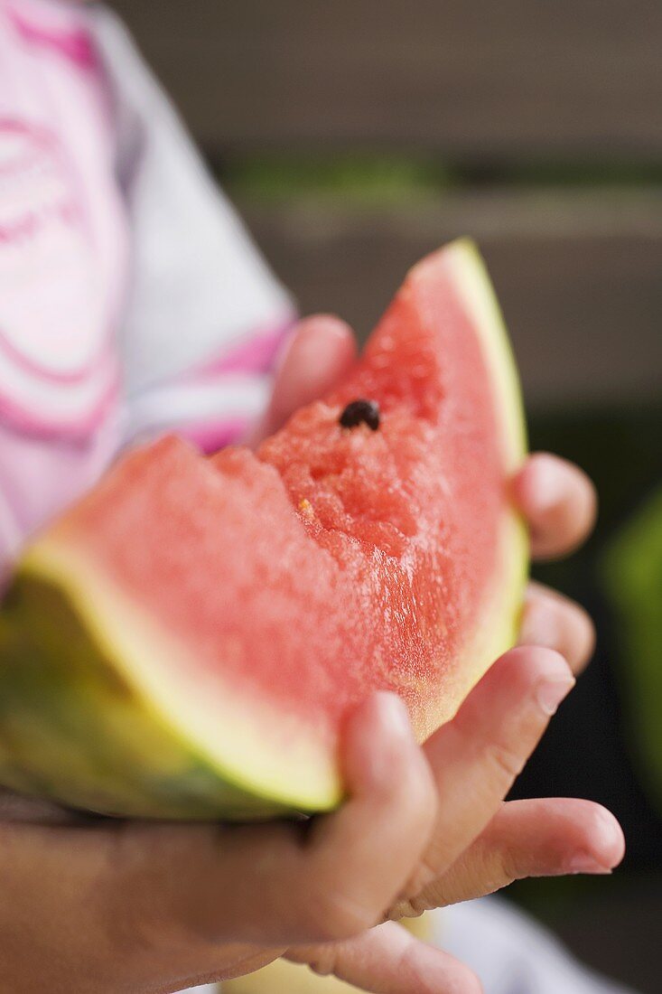 Kinderhände halten Wassermelonenspalte