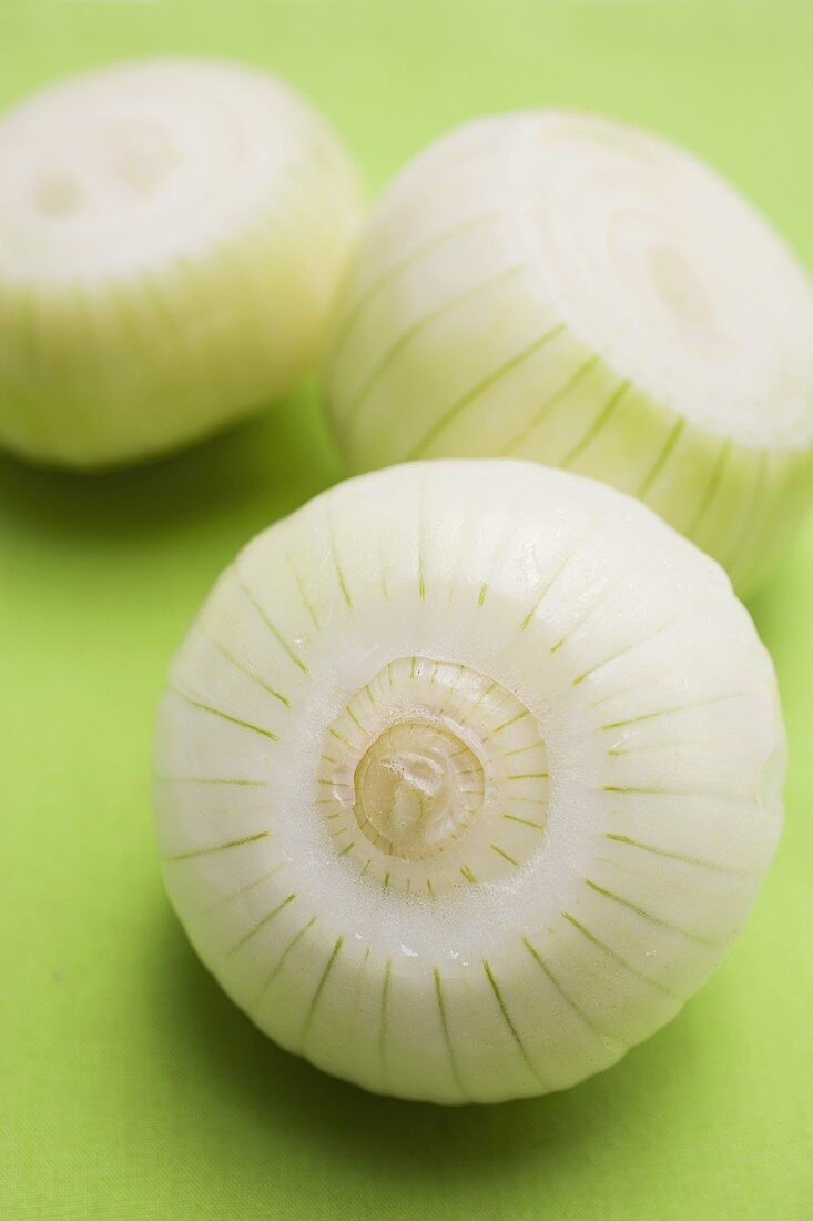 Three white onions, each with a slice cut off