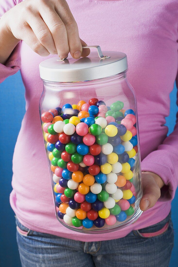 Woman holding jar of coloured bubblegum balls