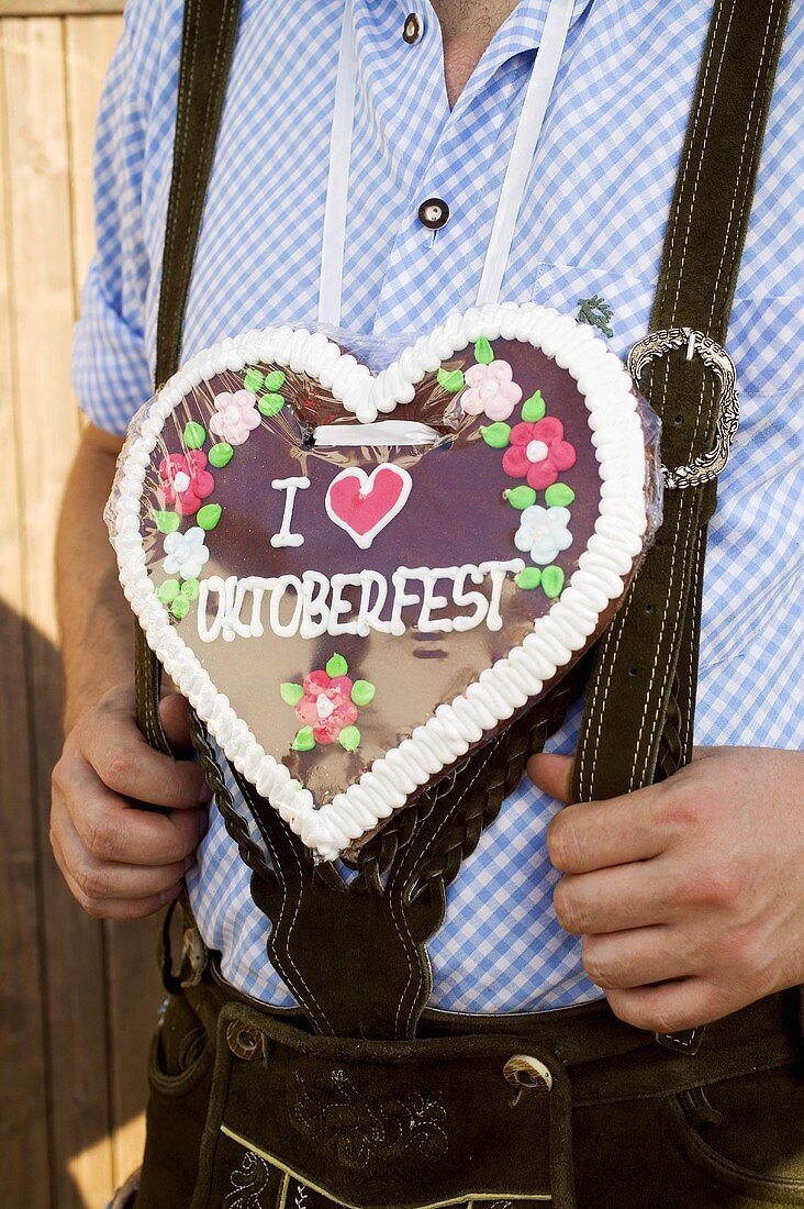 Man in national dress with Lebkuchen heart (Oktoberfest, Munich)