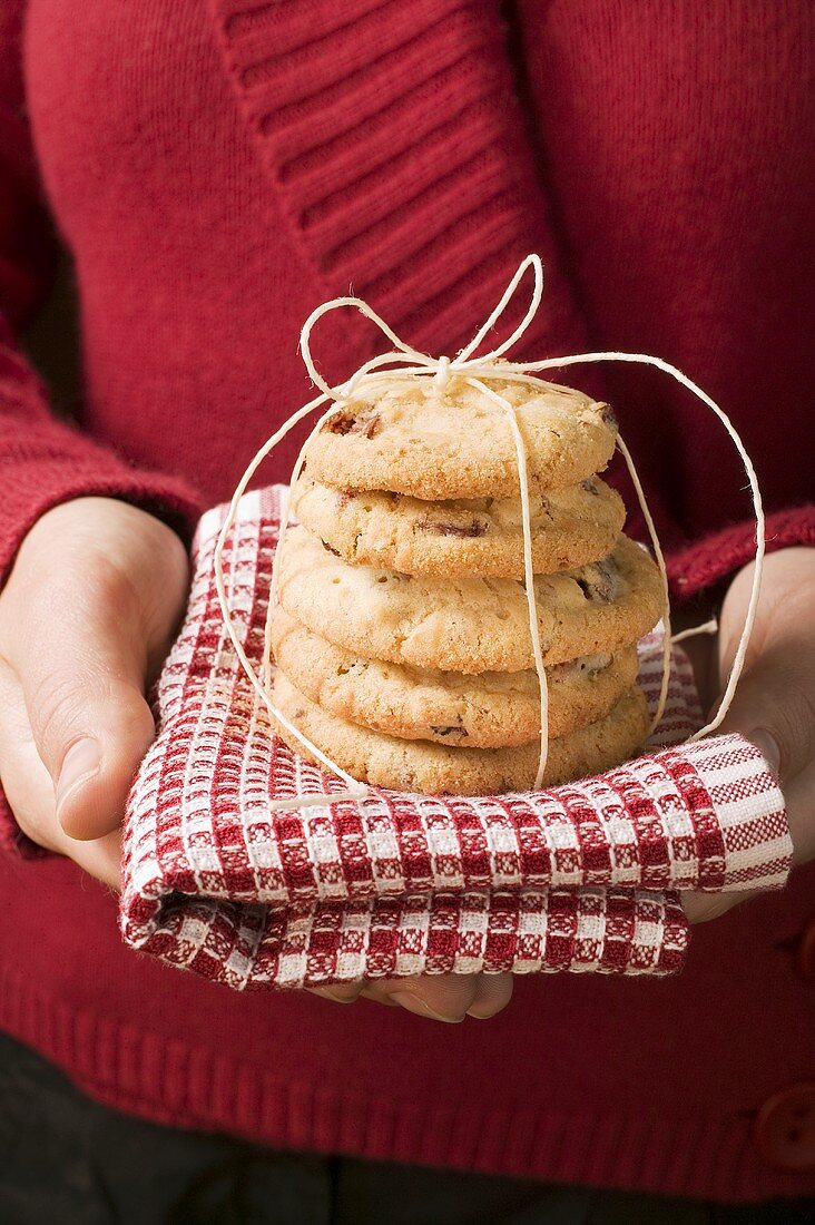 Hände halten Cranberryplätzchen auf kariertem Tuch