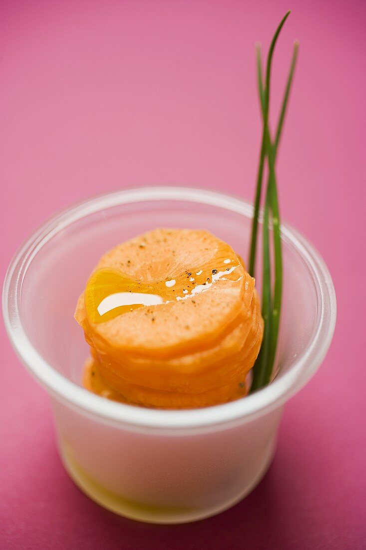 Carrot slices with oil and chives in a small dish