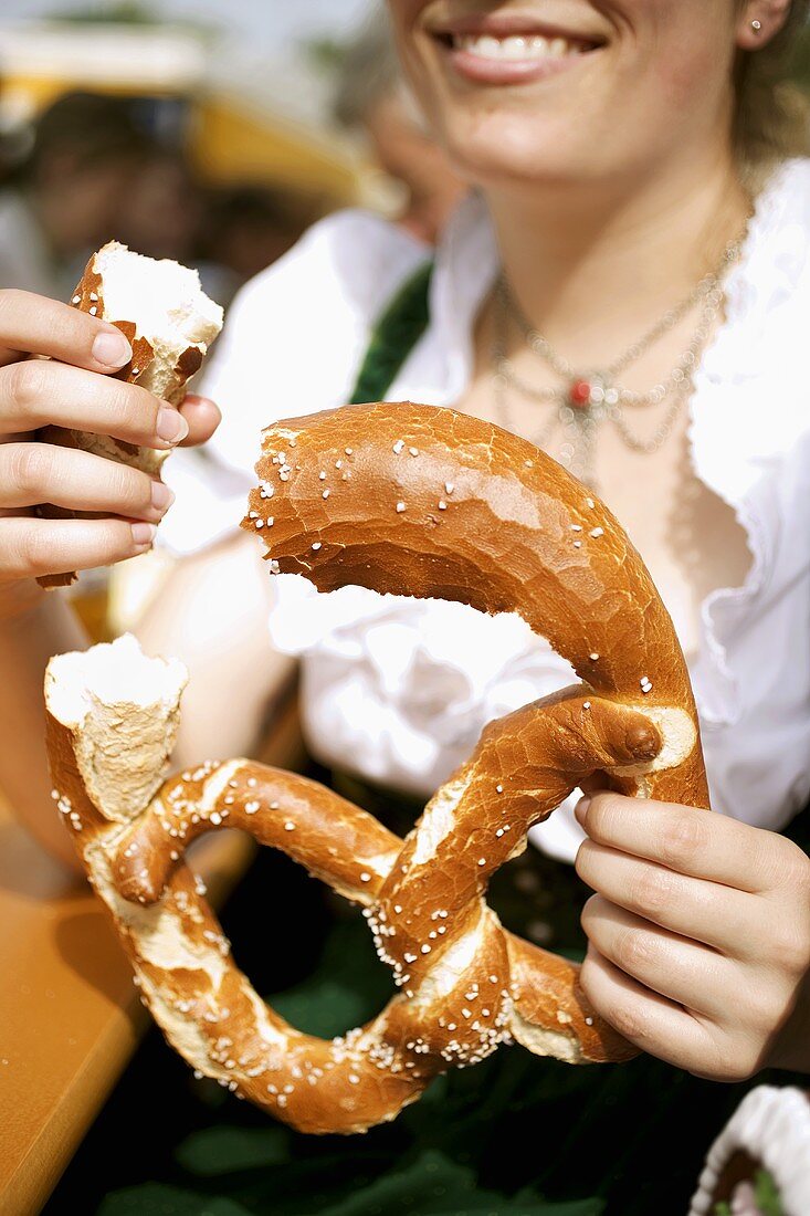 Frau in Tracht isst Laugenbrezel (München, Oktoberfest)