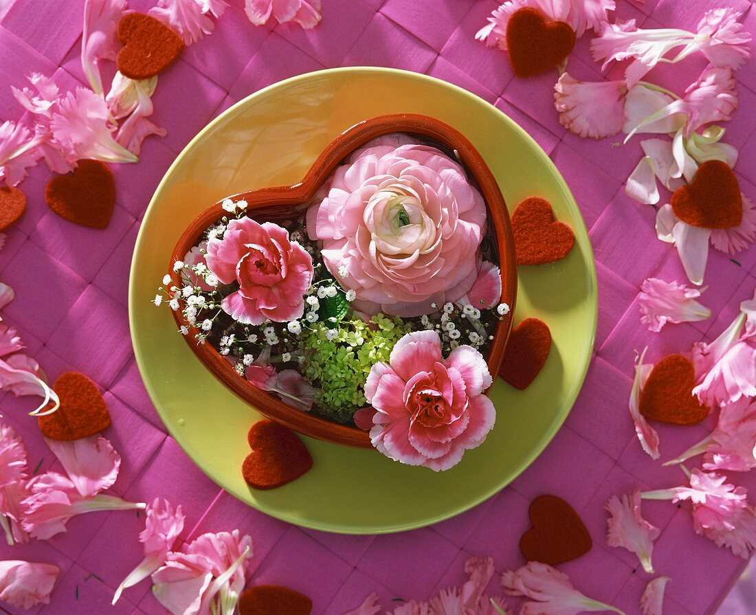Carnations, ranunculi & gypsophila in red heart-shaped bowl