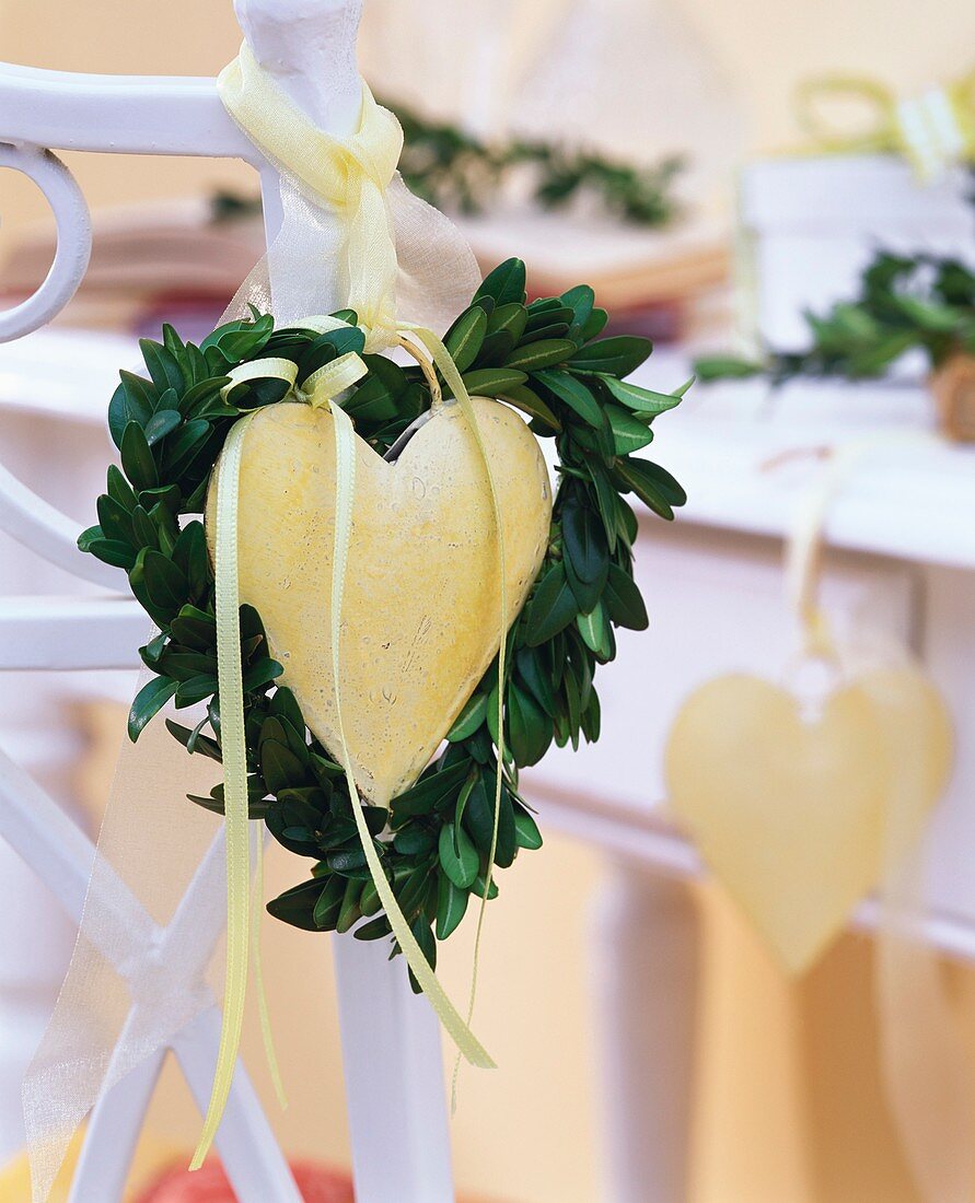 Heart-shaped box wreath around metal heart on chair back