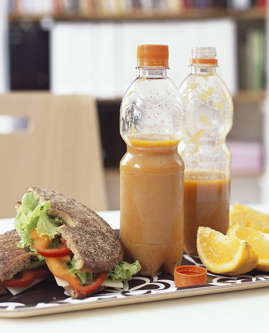 Gemüsesuppe in Flaschen, Sandwich und Orangen zum Lunch