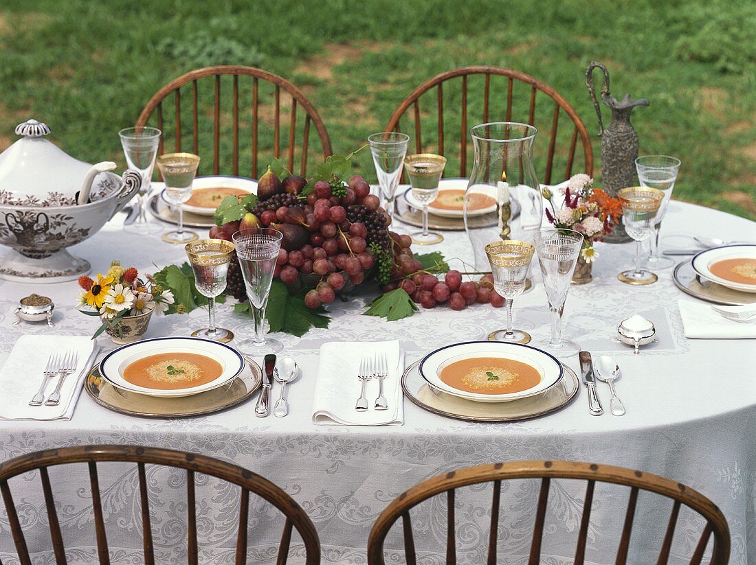 Laid table in the open air with soup and fruit