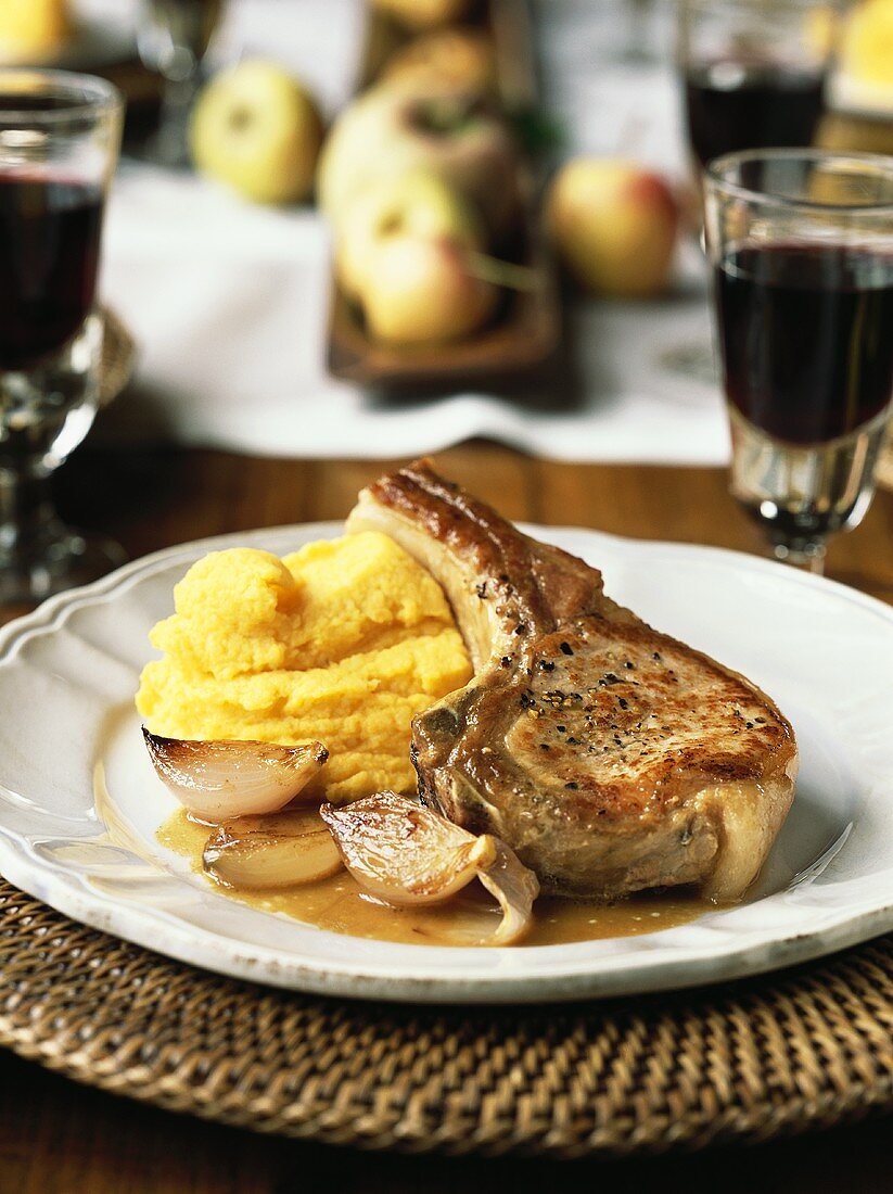 A pork chop with shallots and mashed potatoes