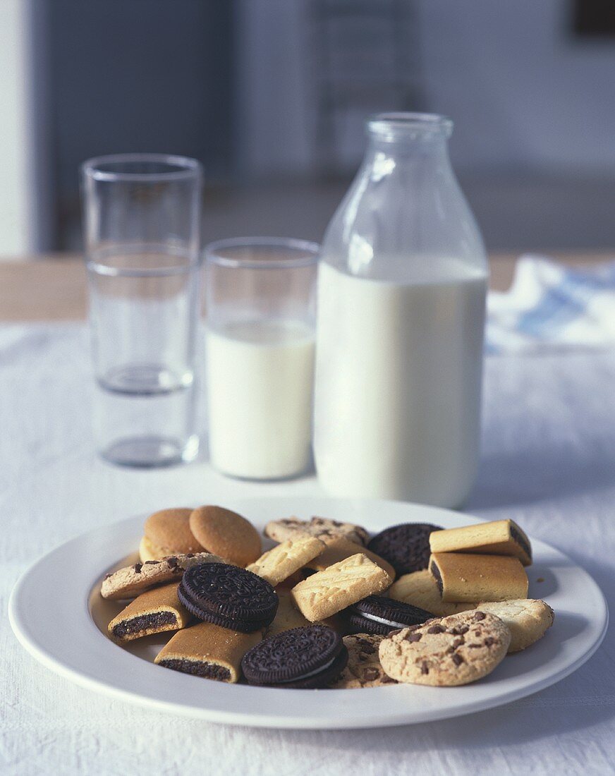 Assorted biscuits on plate, milk in bottle and glass