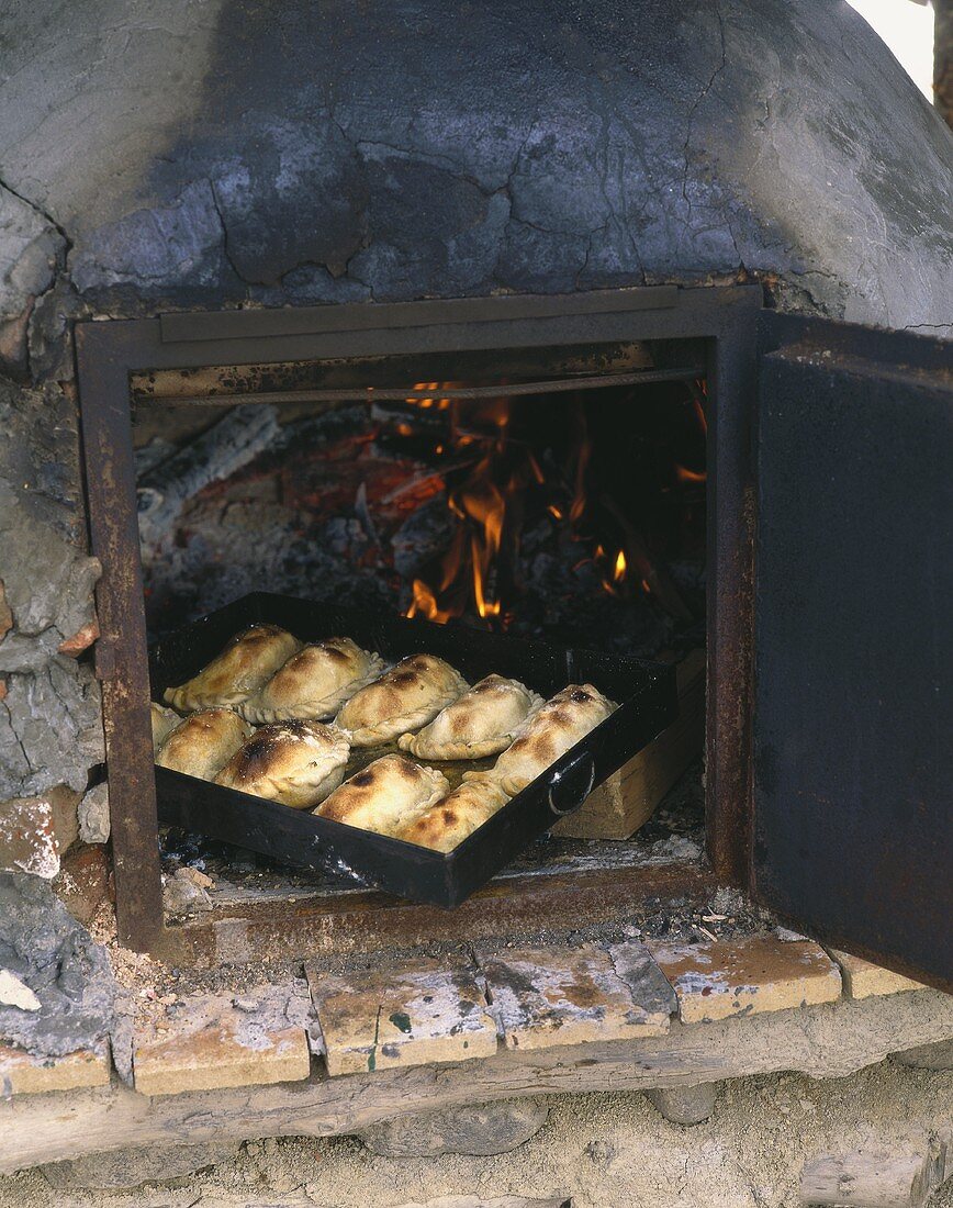 Several calzone on baking tray in wood oven