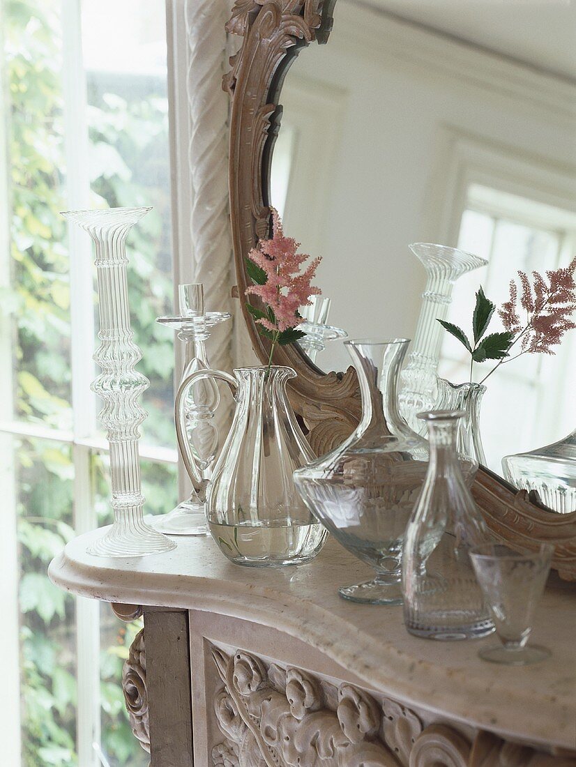 Delicate flowers in glass vases in front of mirror