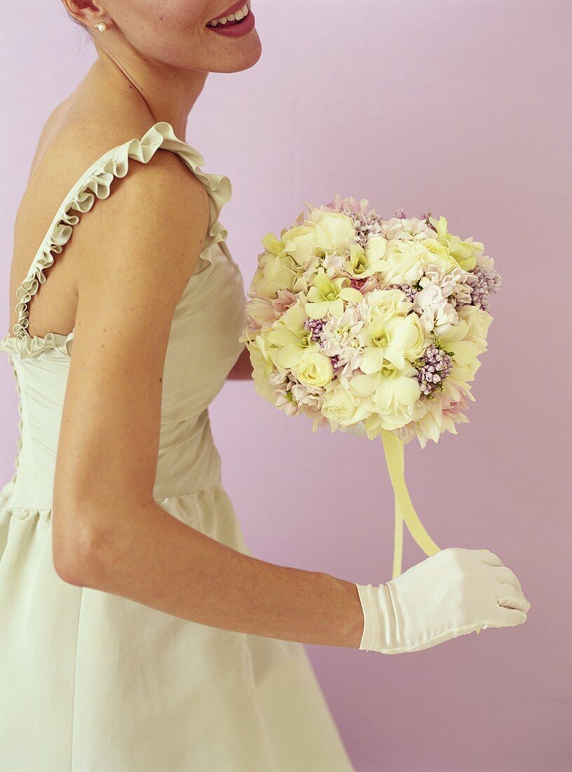 Braut hält Blumenstrauss mit weissen Rosen und Flieder