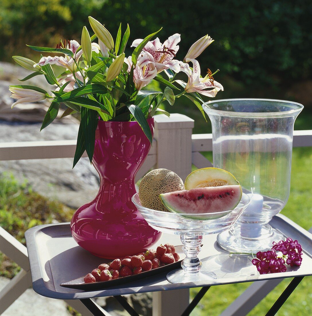 Lilienstrauss und frisches Obst auf Tisch im Freien