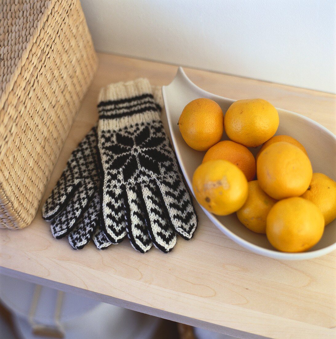 Mandarinen in Schale, daneben Winterhandschuhe