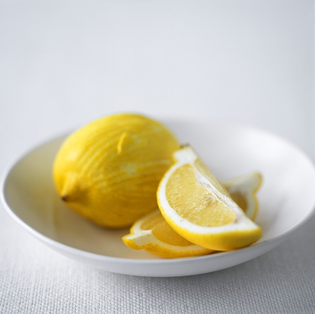 Zitronenschnitze und Zitrone in einem Schälchen