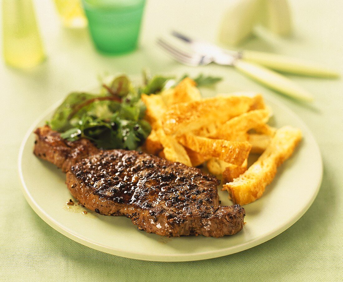 Peppered steak with strips of bread and salad