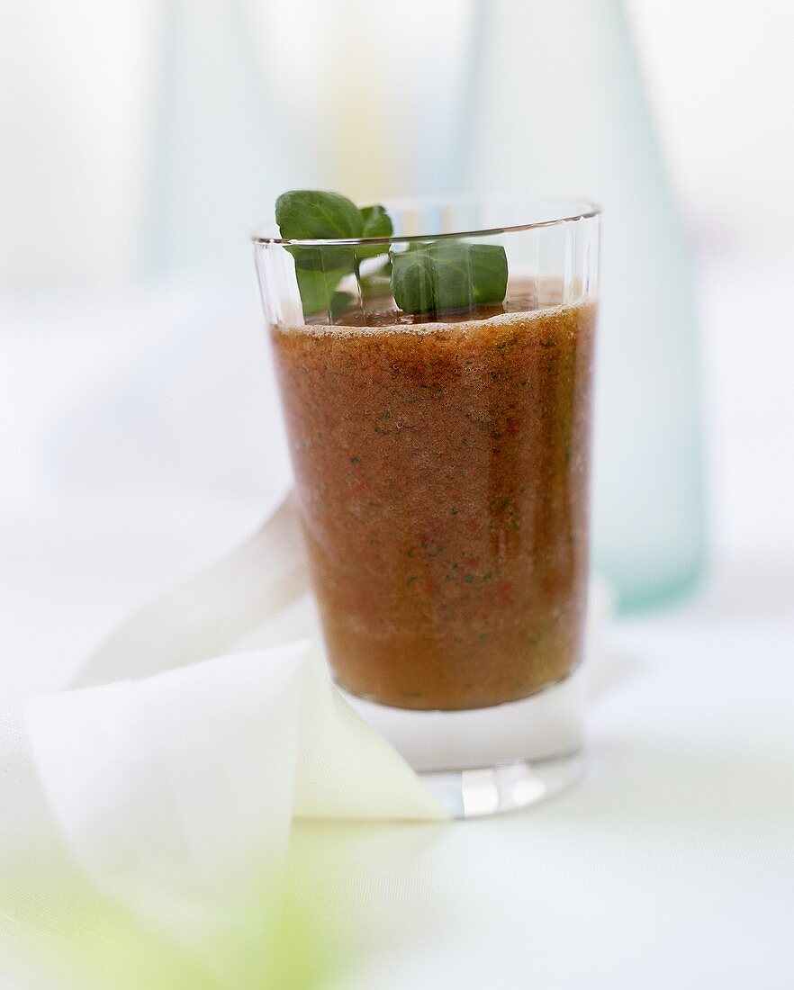 A glass of tomato smoothie with herbs