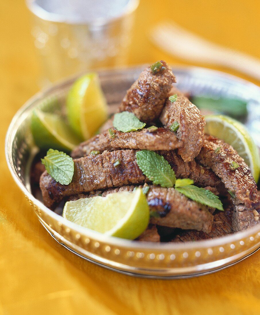 Strips of beef with limes and mint leaves