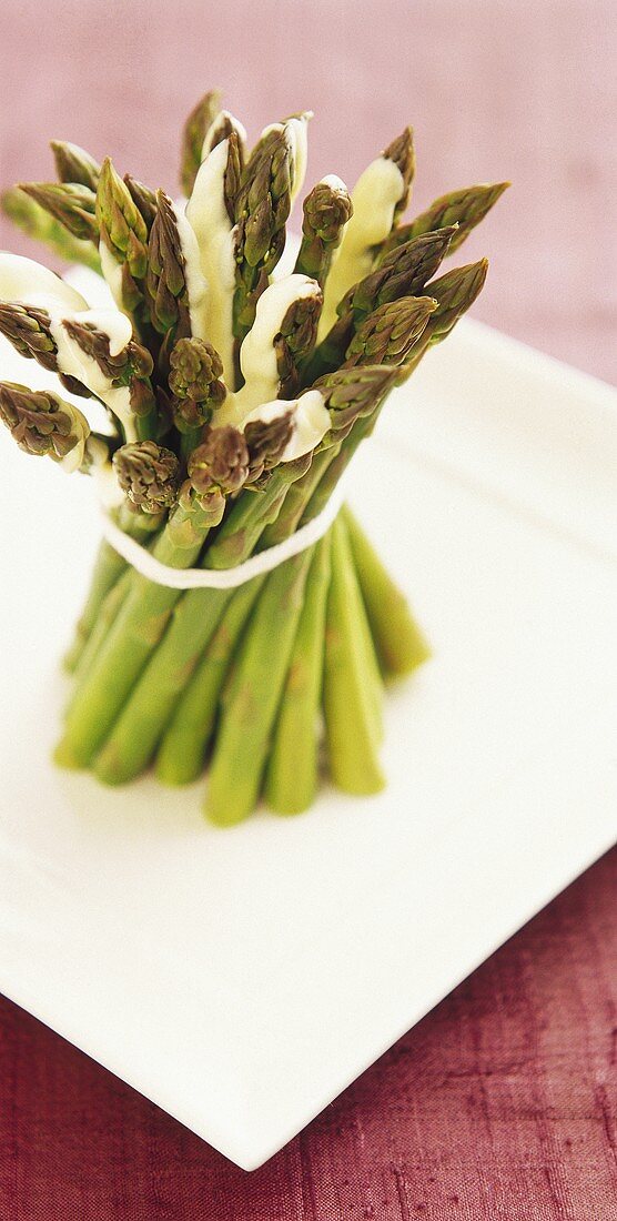 A bundle of green asparagus with white sauce