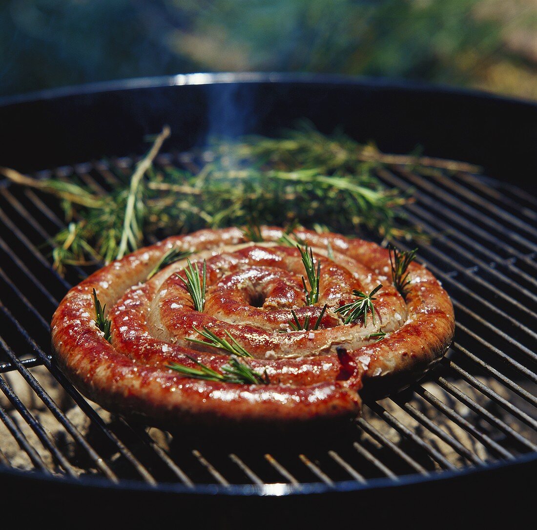 Coiled sausage with rosemary on the barbecue