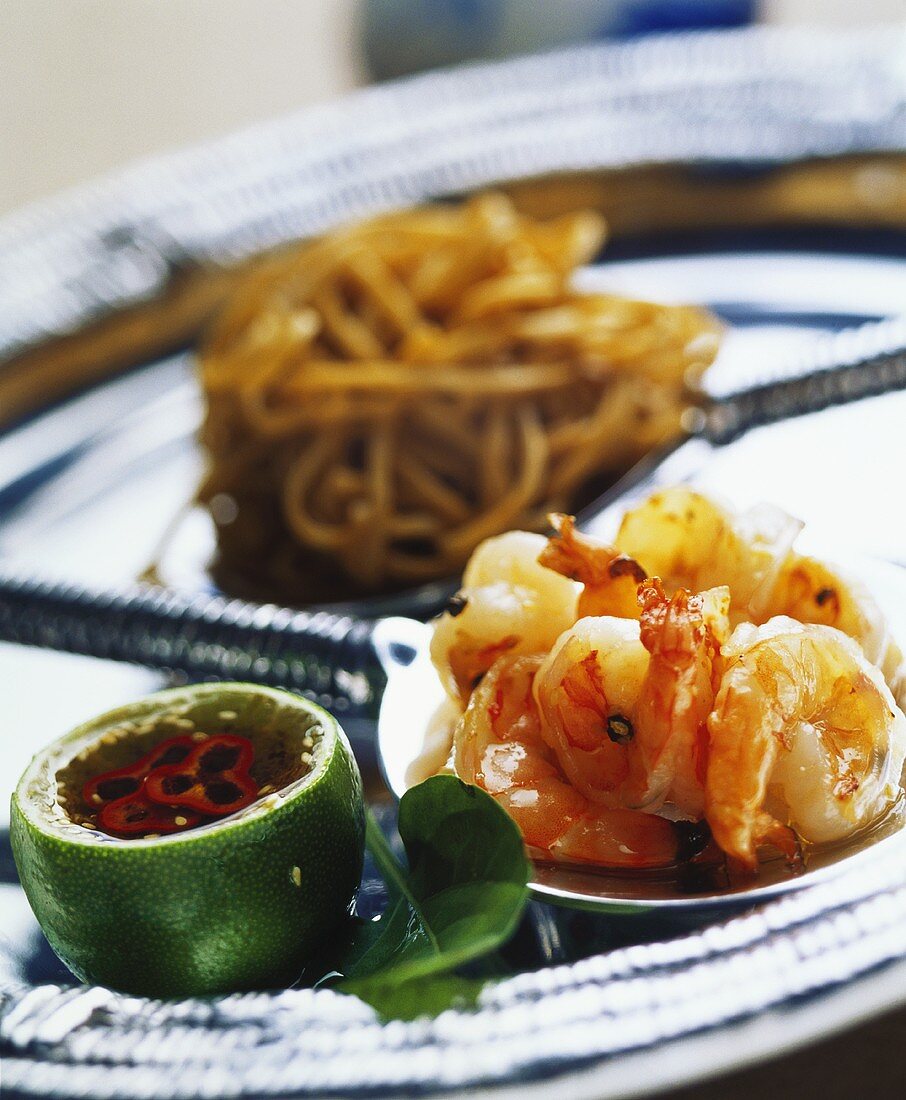 Shrimps and noodles on ladle and chili sauce in lime