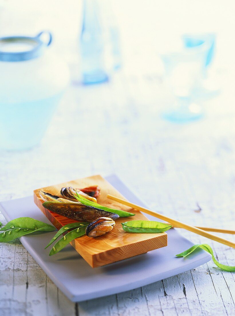 Mussels and mangetout peas on Japanese wooden board
