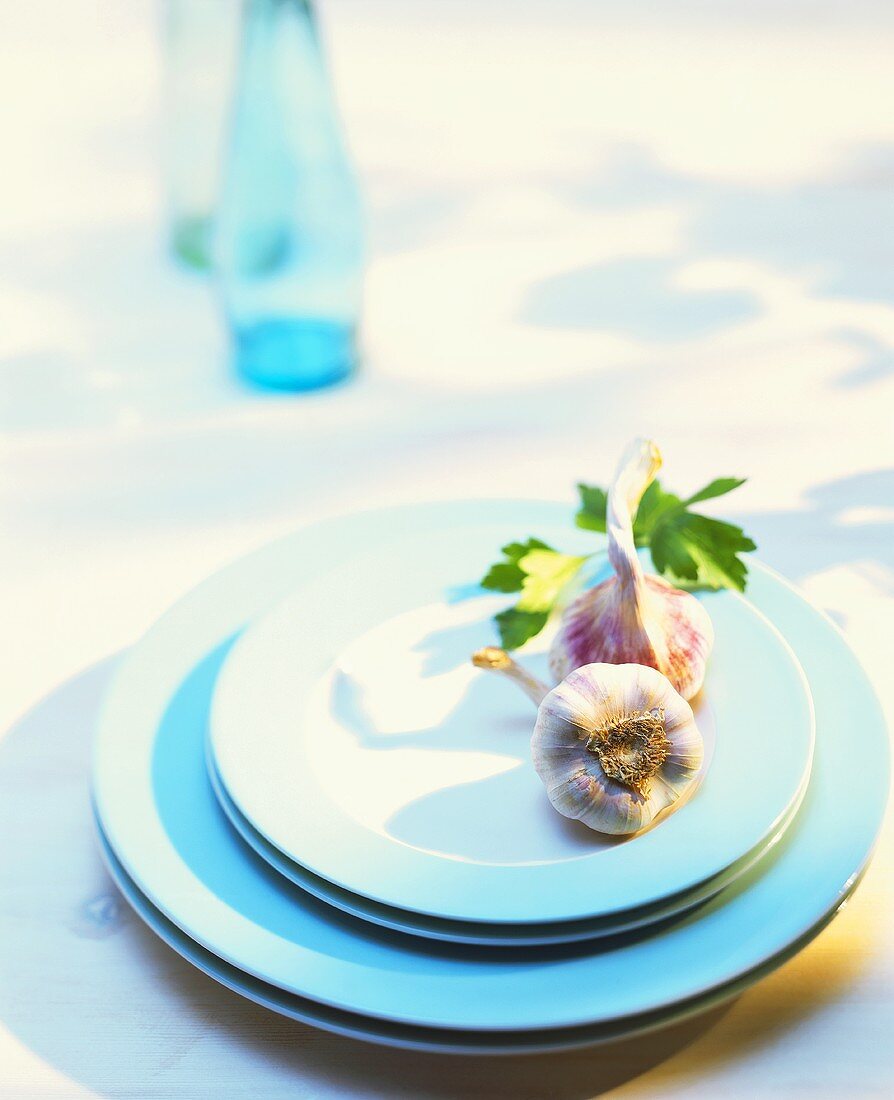 Two garlic bulbs on pale-blue plates